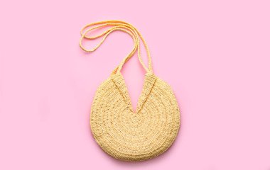 Pembe arka planda zarif bir kadının saman çantası.