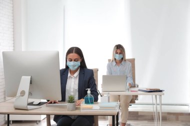 Ofis çalışanları iş yerinde solunum maskesi takıyor.
