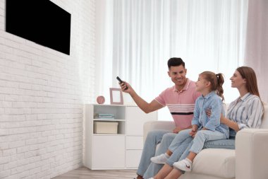 Mutlu bir aile evdeki kanepede televizyon izliyor.