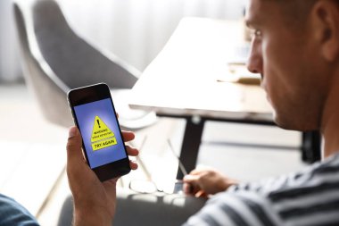 Man holding smartphone with warning about virus attack at home, closeup clipart
