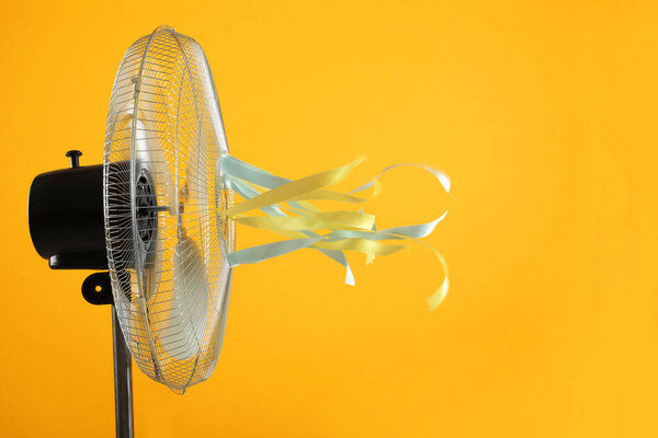 Electric fan on yellow background. Summer heat