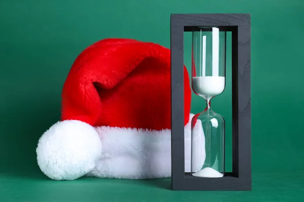 Hourglass Και Σάντα Καπέλο Πράσινο Φόντο Χριστουγεννιάτικη Αντίστροφη Μέτρηση — Φωτογραφία Αρχείου