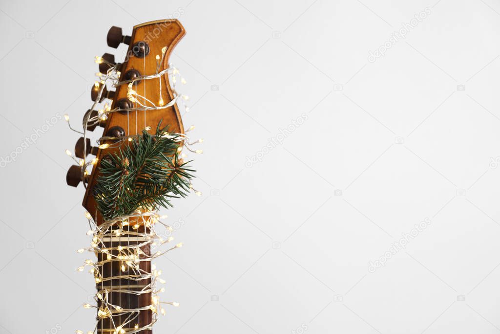 Guitar with fairy lights and fir branch on white background. Christmas music