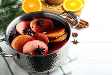 Lezzetli sıcak şarap ve malzemeler beyaz ahşap masada.