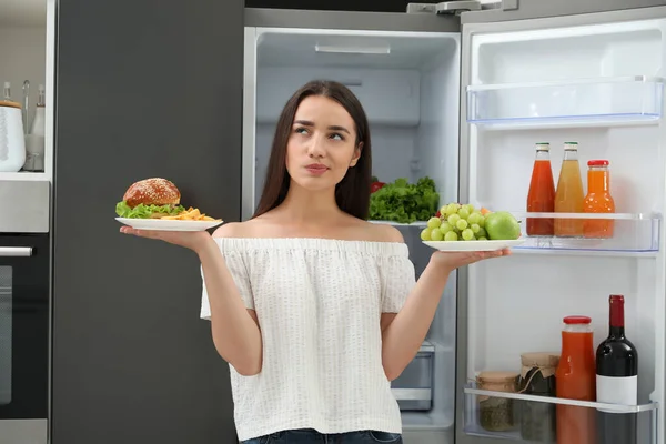 Mulher Escolhendo Entre Frutas Hambúrguer Com Batatas Fritas Perto Geladeira — Fotografia de Stock