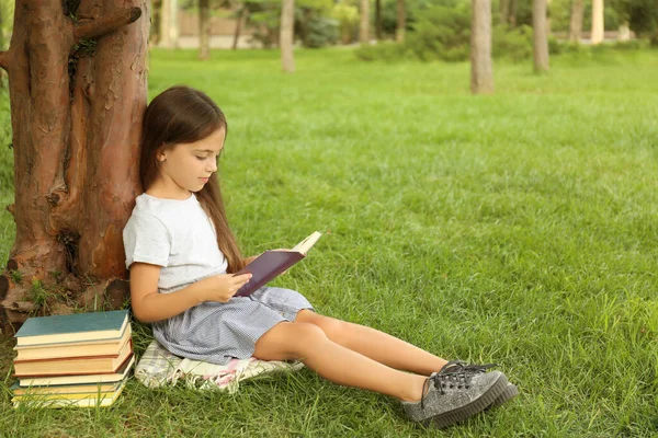 Linda Niña Leyendo Libro Sobre Hierba Verde Cerca Del Árbol — Foto de Stock