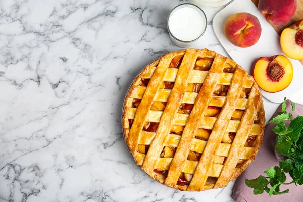 Delicious peach pie and fresh fruits on white marble table, flat lay. Space for text