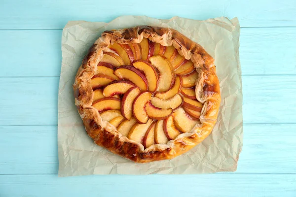 Delicious fresh peach pie on light blue wooden table, top view