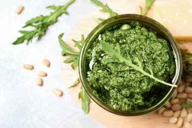 Bir kase lezzetli roka pesto ve malzemeler ışık masasında, düz yatıyordu.