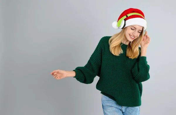 灰色の背景にヘッドフォンを持つ幸せな女性 テキストのためのスペース クリスマス音楽 — ストック写真