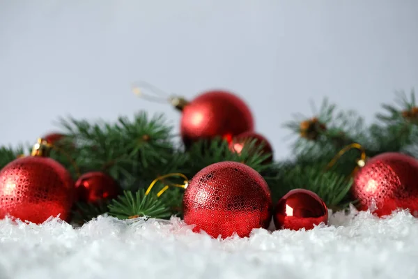 Schöne Weihnachtskugeln Und Tannenzweige Auf Schnee Vor Grauem Hintergrund Raum — Stockfoto