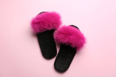 Açık pembe arka planda bir çift yumuşak terlik.