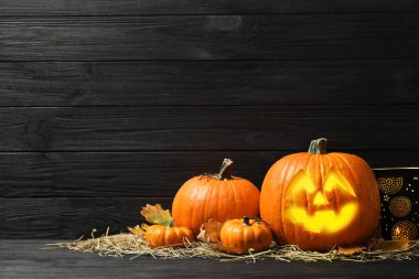 Jack O 'Lantern, balkabakları ve saman siyah ahşap masa üzerinde, yazı için yer. Cadılar Bayramı Dekorasyonu