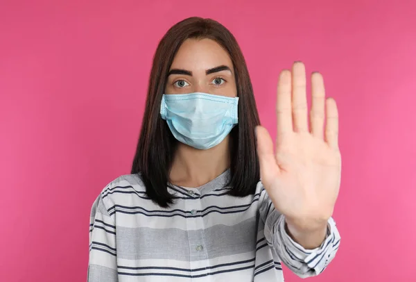 Νεαρή Γυναίκα Προστατευτική Μάσκα Που Δείχνει Χειρονομία Στοπ Ροζ Φόντο — Φωτογραφία Αρχείου