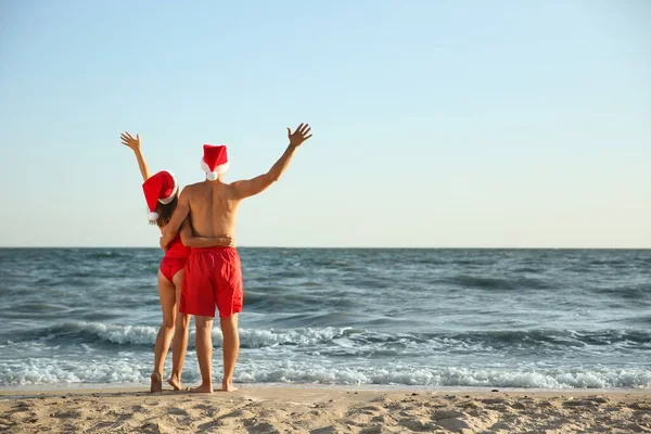 Piękna Para Kapeluszami Mikołaja Razem Plaży Widok Tyłu Święta Bożego — Zdjęcie stockowe