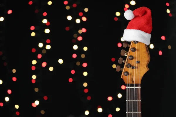 Gitaar Met Kerstmuts Tegen Wazig Licht Ruimte Voor Tekst Kerstmuziek — Stockfoto
