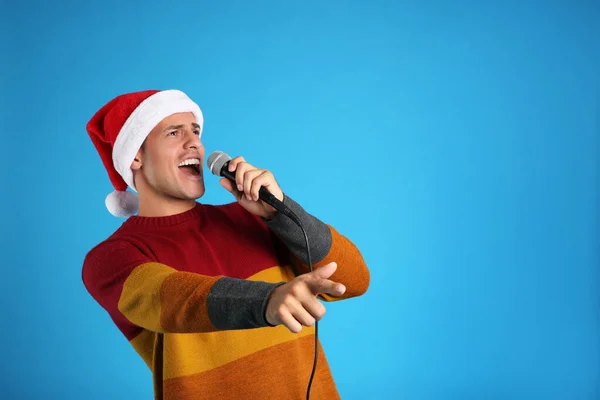 Емоційний Чоловік Капелюсі Санта Клауса Співає Мікрофоном Синьому Фоні Простір — стокове фото