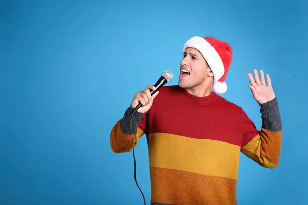 Емоційний Чоловік Капелюсі Санта Клауса Співає Мікрофоном Синьому Фоні Простір — стокове фото