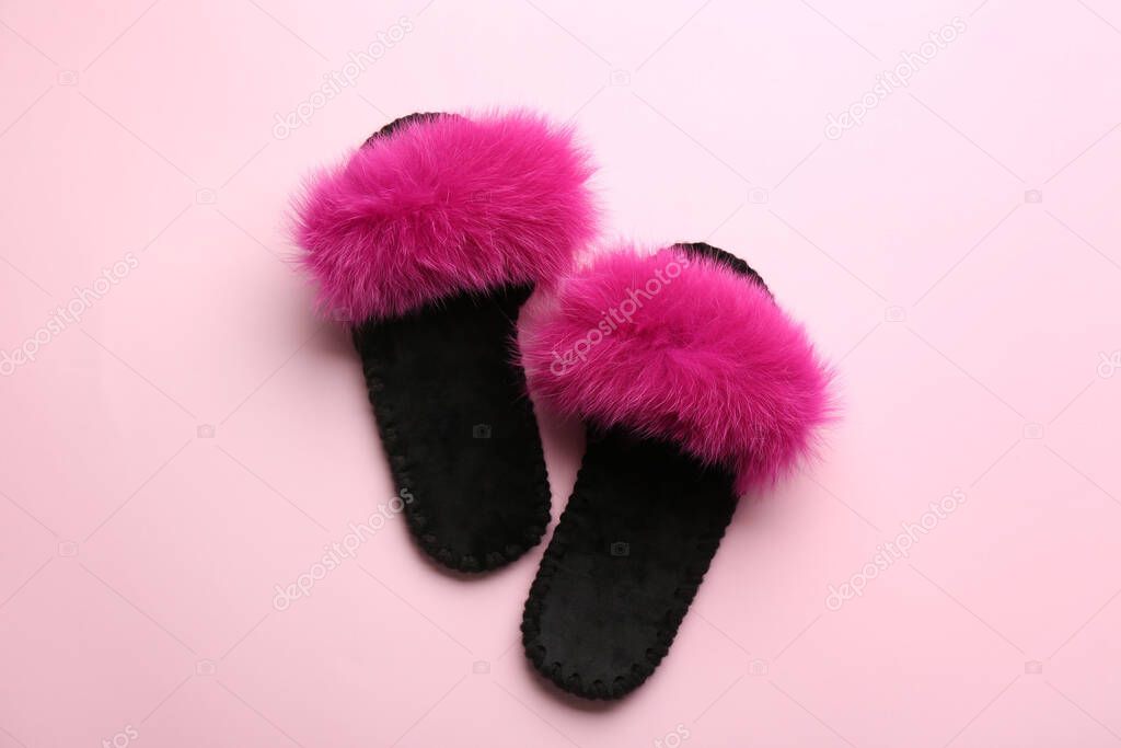 Pair of soft slippers on light pink background, flat lay