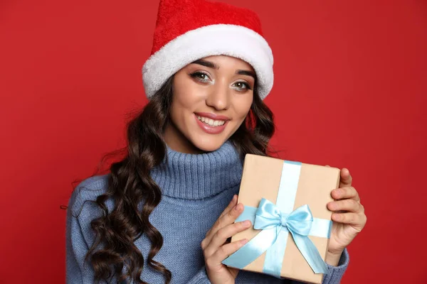 Красивая Женщина Шляпе Санты Рождественским Подарком Красном Фоне — стоковое фото