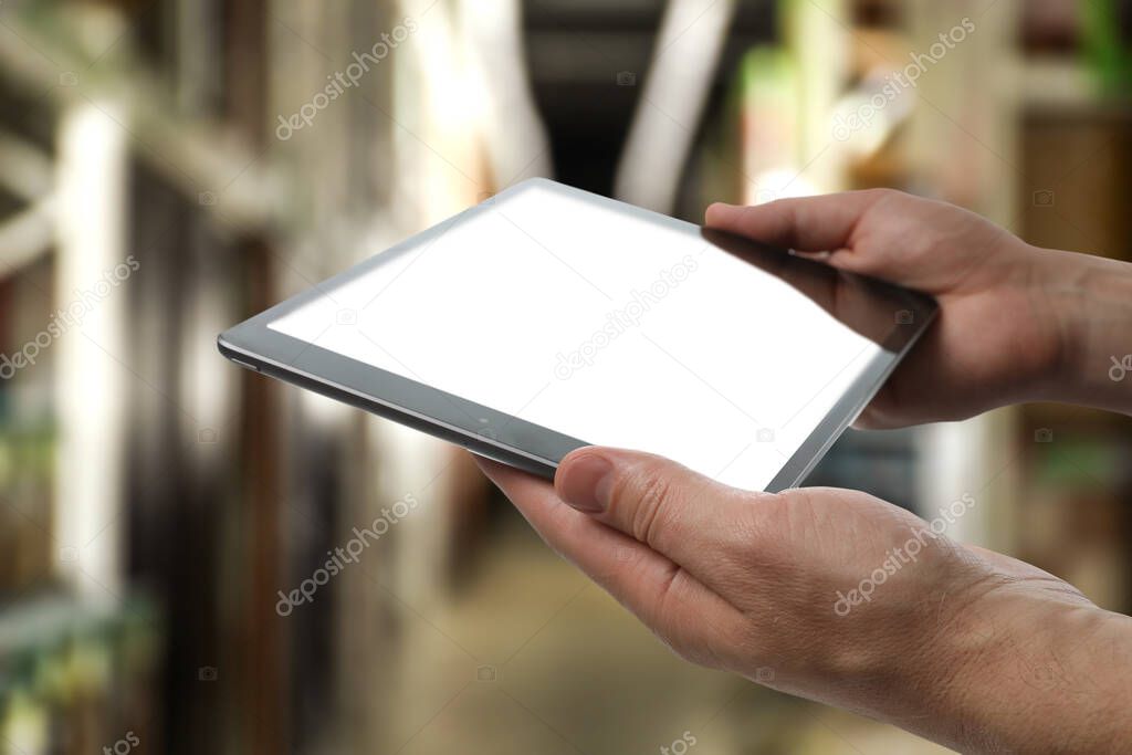Wholesale trading. Man using WMS app on tablet at warehouse, closeup 