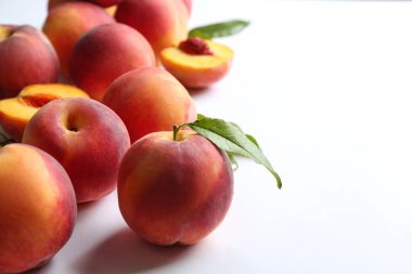 Taze şeftaliler ve beyaz arka planda yeşil yapraklar, yakın plan. Metin için boşluk