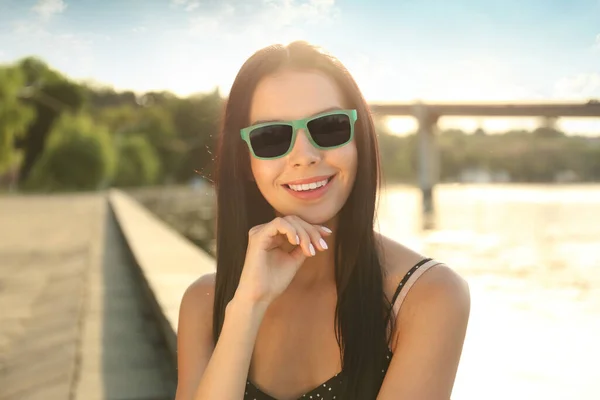 Piękna Młoda Kobieta Nosi Stylowe Okulary Przeciwsłoneczne Pobliżu Rzeki — Zdjęcie stockowe