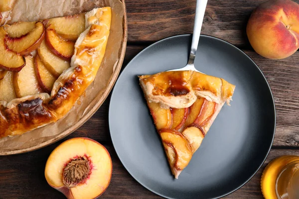 Delicious fresh peach pie served on wooden table, flat lay