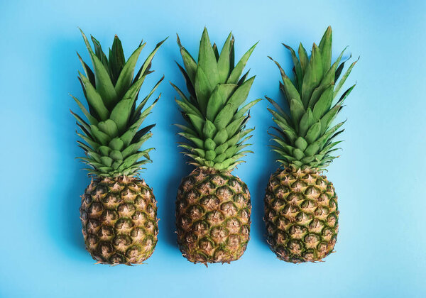 Fresh ripe juicy pineapples on light blue background, flat lay