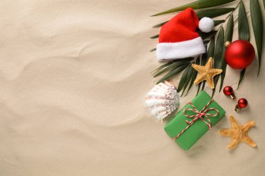 Noel Baba şapkası ve kumdaki deniz yıldızlarıyla bezenmiş düz bir kompozisyon, yazı için boşluk. Noel tatili