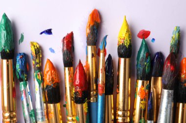 Beyaz arka planda renkli boyalı fırçalar, düz bir zemin