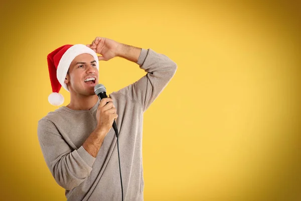 Emocjonalny Mężczyzna Kapeluszu Świętego Mikołaja Śpiewający Mikrofonem Żółtym Tle Miejsce — Zdjęcie stockowe