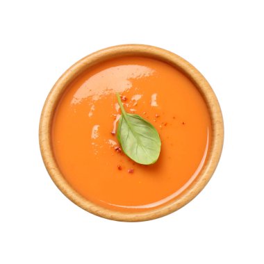 Beyaz arka planda fesleğenli lezzetli kremalı balkabağı çorbası.