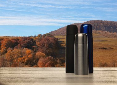 Arkaplanda termoslu ahşap masa ve dağ manzarası