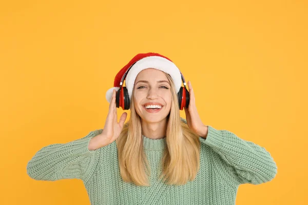 黄色の背景にヘッドフォンを持つ幸せな女性 クリスマス音楽 — ストック写真