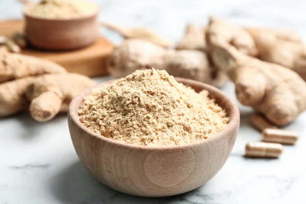 Dry ginger powder in bowl on white marble table