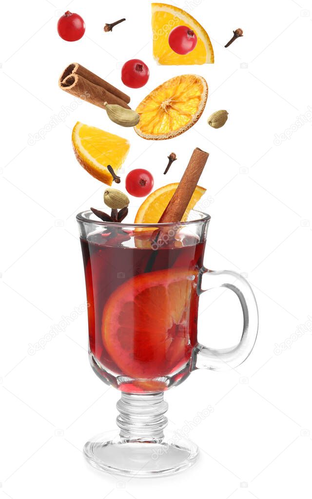 Cut orange, cranberries and different spices falling into glass cup of mulled wine on white background 