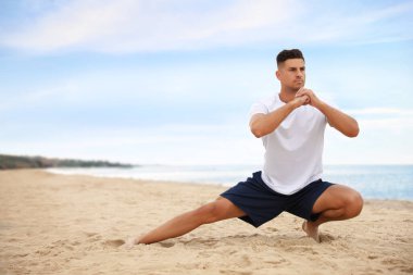 Kaslı adam plajda egzersiz yapıyor, mesaj için yer var. Vücut eğitimi