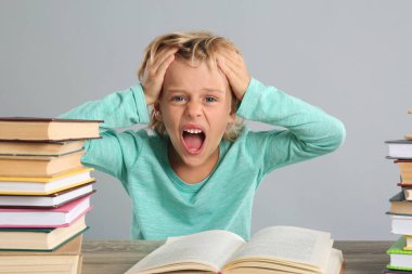 Duygusal küçük çocuk gri arka planla ilgili ödev yapıyor.