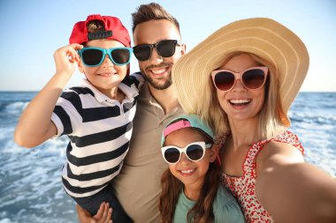 Mutlu aile deniz kenarında selfie çekiyor. Yaz tatili