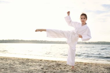 Kimonolu tatlı küçük kız nehir kenarında karate yapıyor.