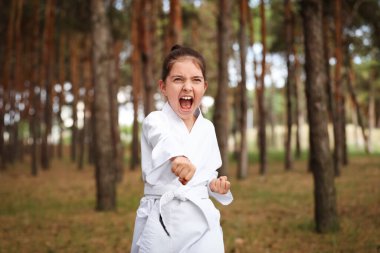 Kimonolu tatlı küçük kız ormanda karate yapıyor.