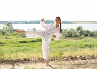 Kimonolu şirin kız dışarıda karate yapıyor.