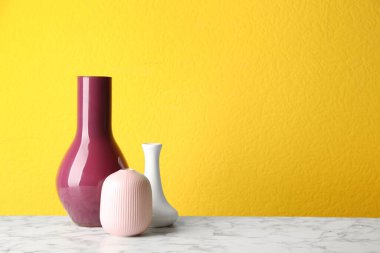 Beyaz mermer masada sarı arka planda seramik vazolar. Metin için boşluk