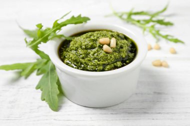 Beyaz ahşap masada bir kase lezzetli pesto ve roka.