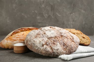 Gri masada farklı taze ekmek türleri.