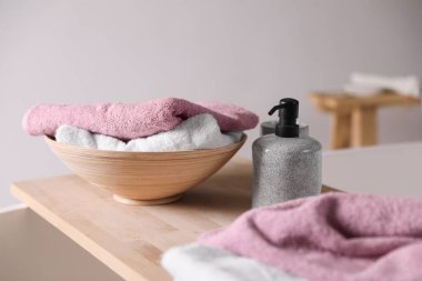 Sabun makinesi ve katlanmış yumuşak havlular banyodaki tahta tahtada.