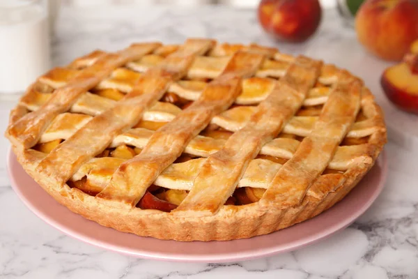 Delicious peach pie and fresh fruits on white marble table, closeup
