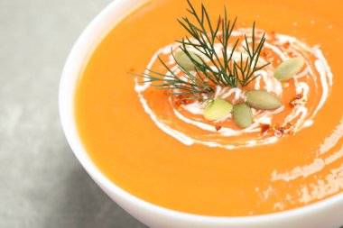 Gri masadaki kasede lezzetli balkabağı çorbası, yakın plan.