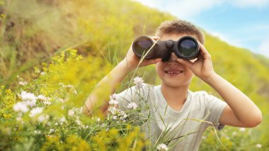 Güneşli bir günde dürbünü olan küçük çocuk.